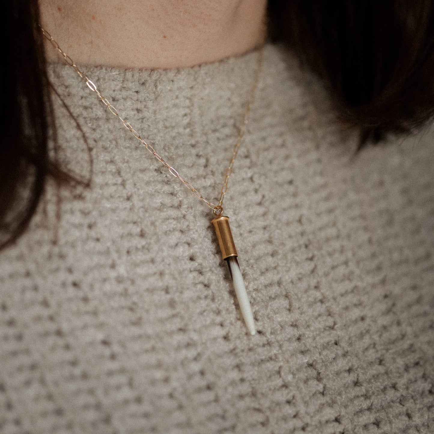 Necklace with a unique pendant worn by a person against a neutral background