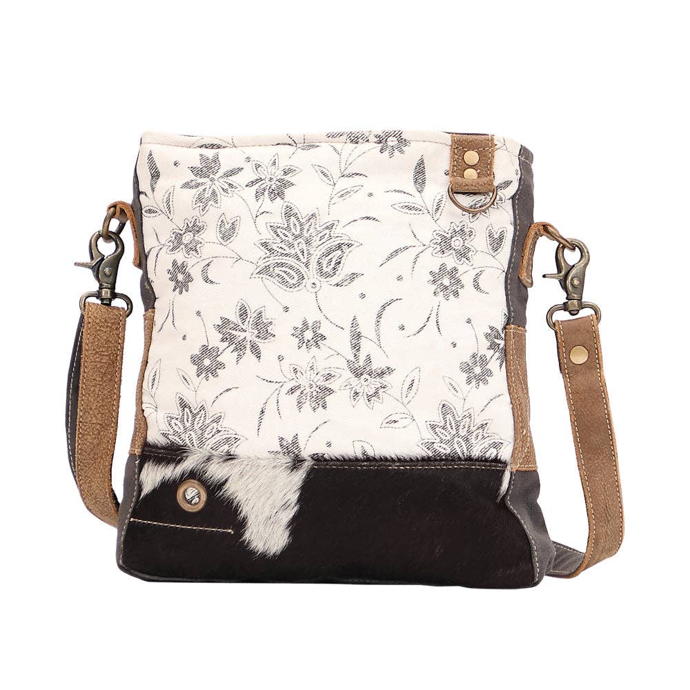 Floral patterned crossbody bag with black accents on a white background