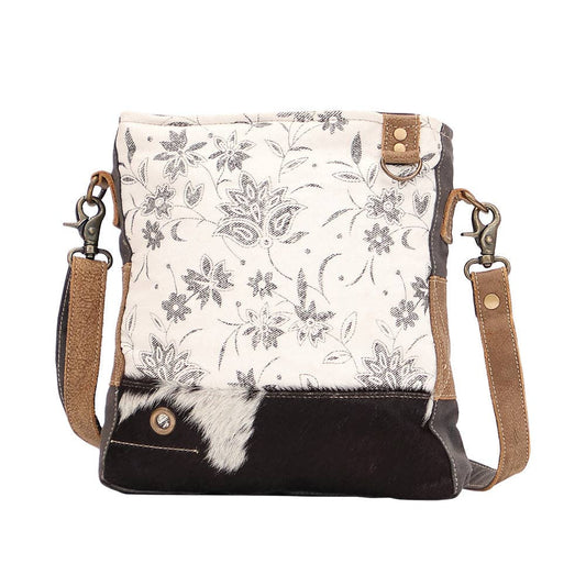 Floral patterned crossbody bag with black accents on a white background