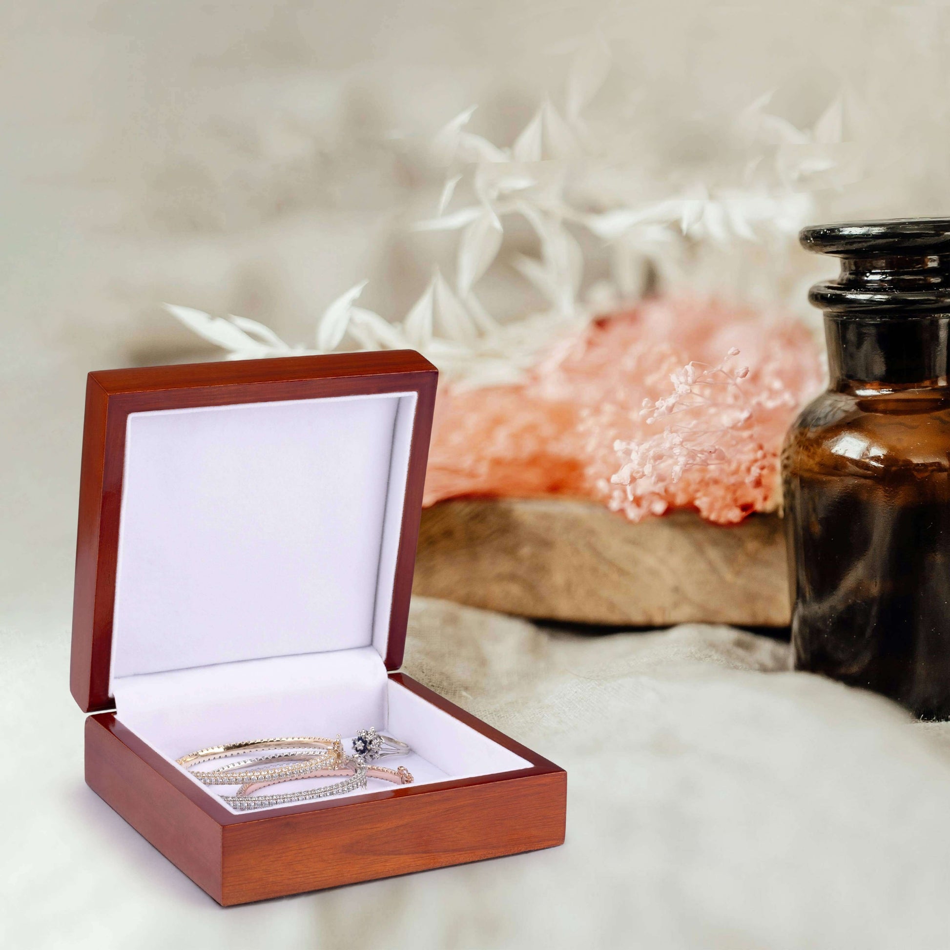 Wooden jewelry box with a ring inside, placed on a soft surface with a blurred background.