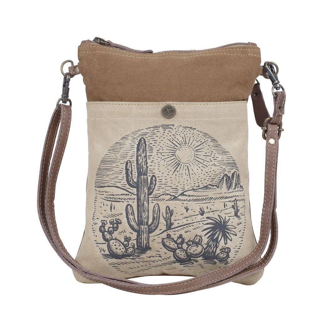 Canvas crossbody bag with desert scene design and brown leather accents on a white background