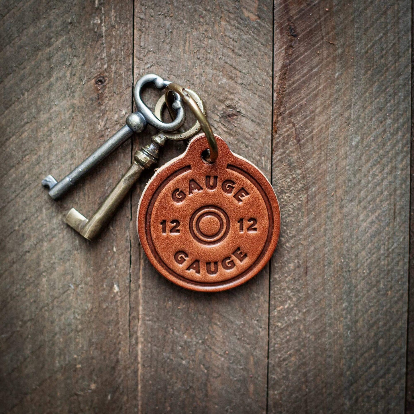 12 Gauge Leather Keychain USA with vintage keys on rustic wooden background.