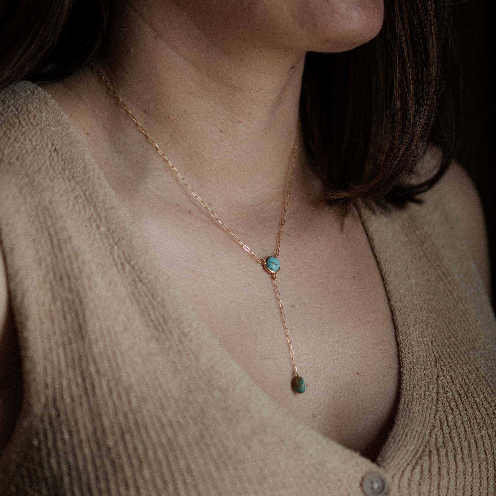 Necklace with turquoise stones worn by a person in a beige sweater.