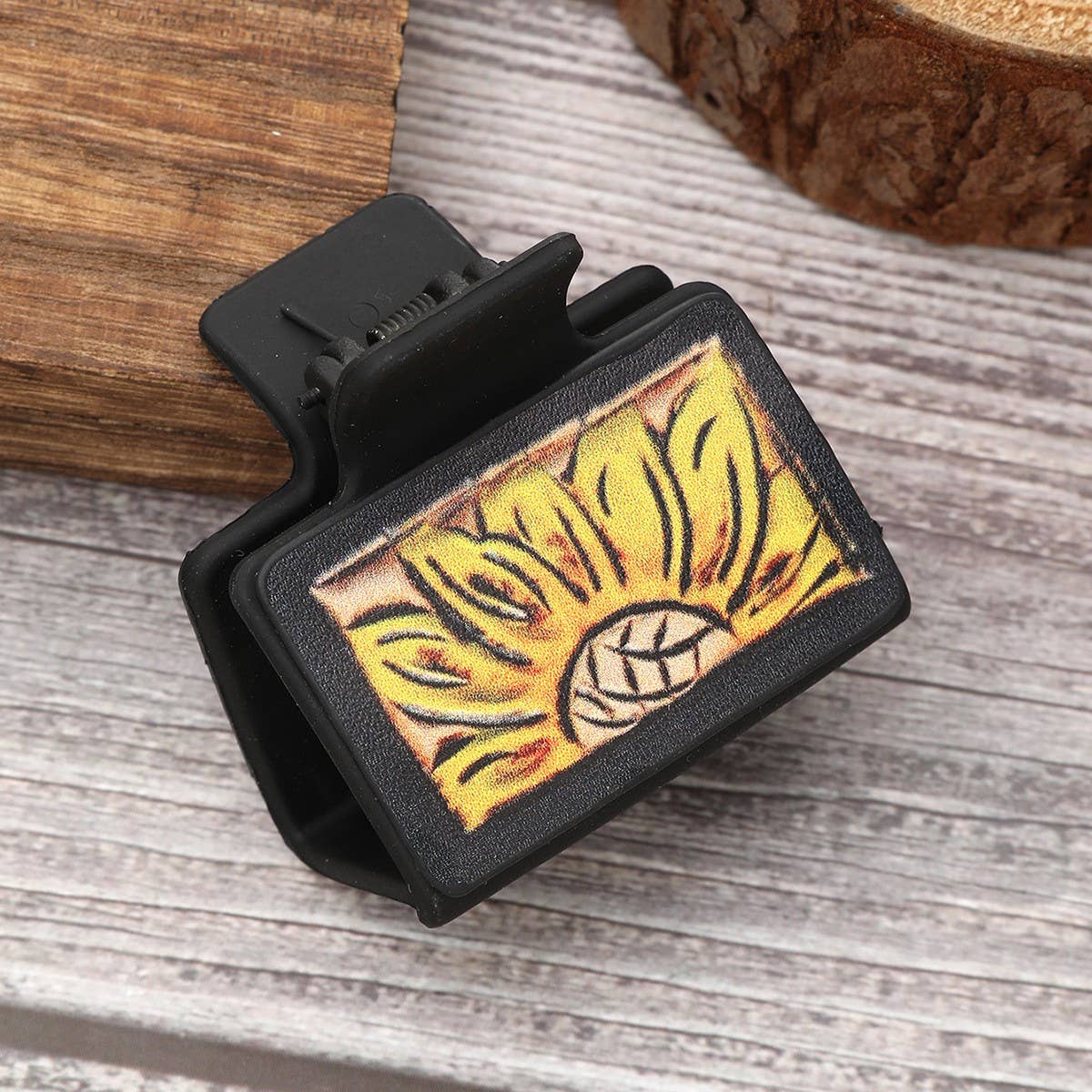 Black clip with sunflower design on a wooden surface