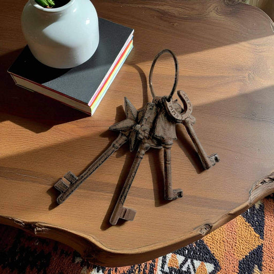 Set of old keys on a wooden surface with a book and white vase in the background.