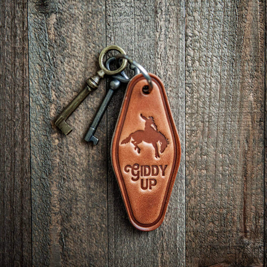 Giddy Up Leather Keychain Motel Style with vintage keys on wooden background.