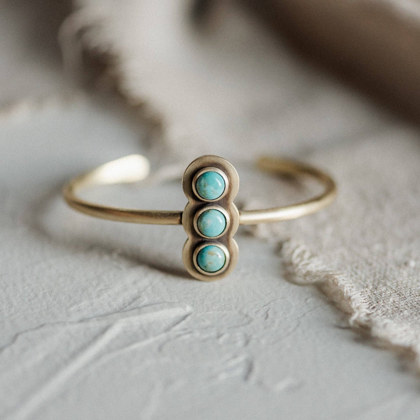 Gold bracelet with turquoise stones on a textured surface