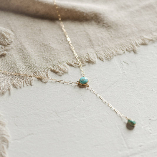 Necklace with turquoise pendant on a textured fabric background