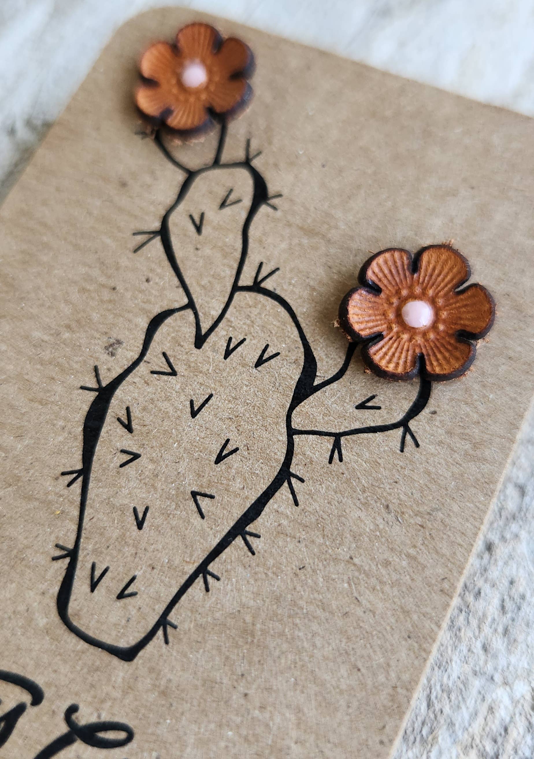 Cactus-shaped earrings with flowers on a kraft paper background