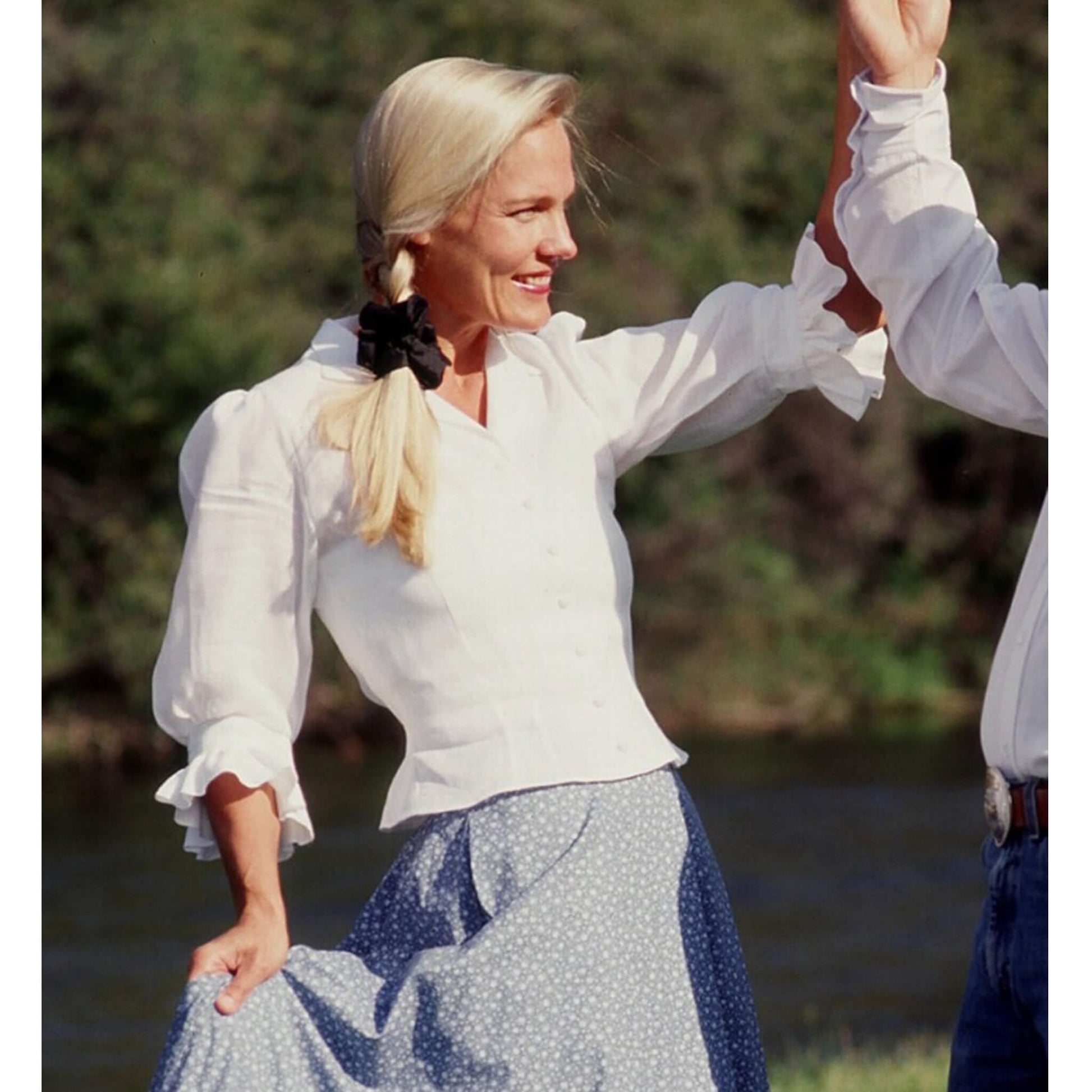 This lovely blouse with its tapered feminine lines and puffy, ruffled ¾ length sleeves will make you look like an angel. This design can be worn tucked in or out and looks great with any skirt or pant. Front closes with seven covered buttons and an elastic band in the back for an easy, comfortable fit. Made in USA