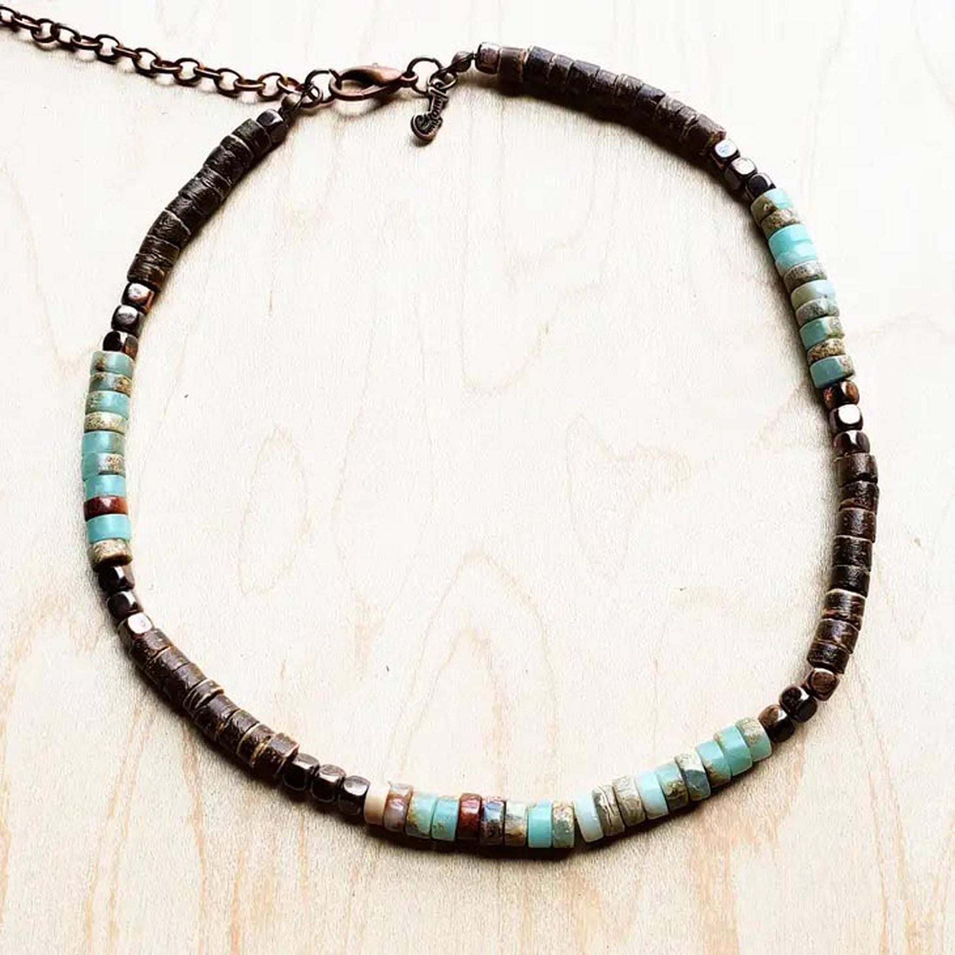 Hand beaded choker necklace features a combination of Genuine aqua terra, wood, and copper beads. Choker is meant to be worn above the collar bone. Great for layering with longer necklaces or worn alone. Entire length of necklace is 15 inches end to end, Which includes an extender chain. 4-6mm beads Although your item will resemble the photo, Each piece is created by hand, so no two are identical. Made in USA