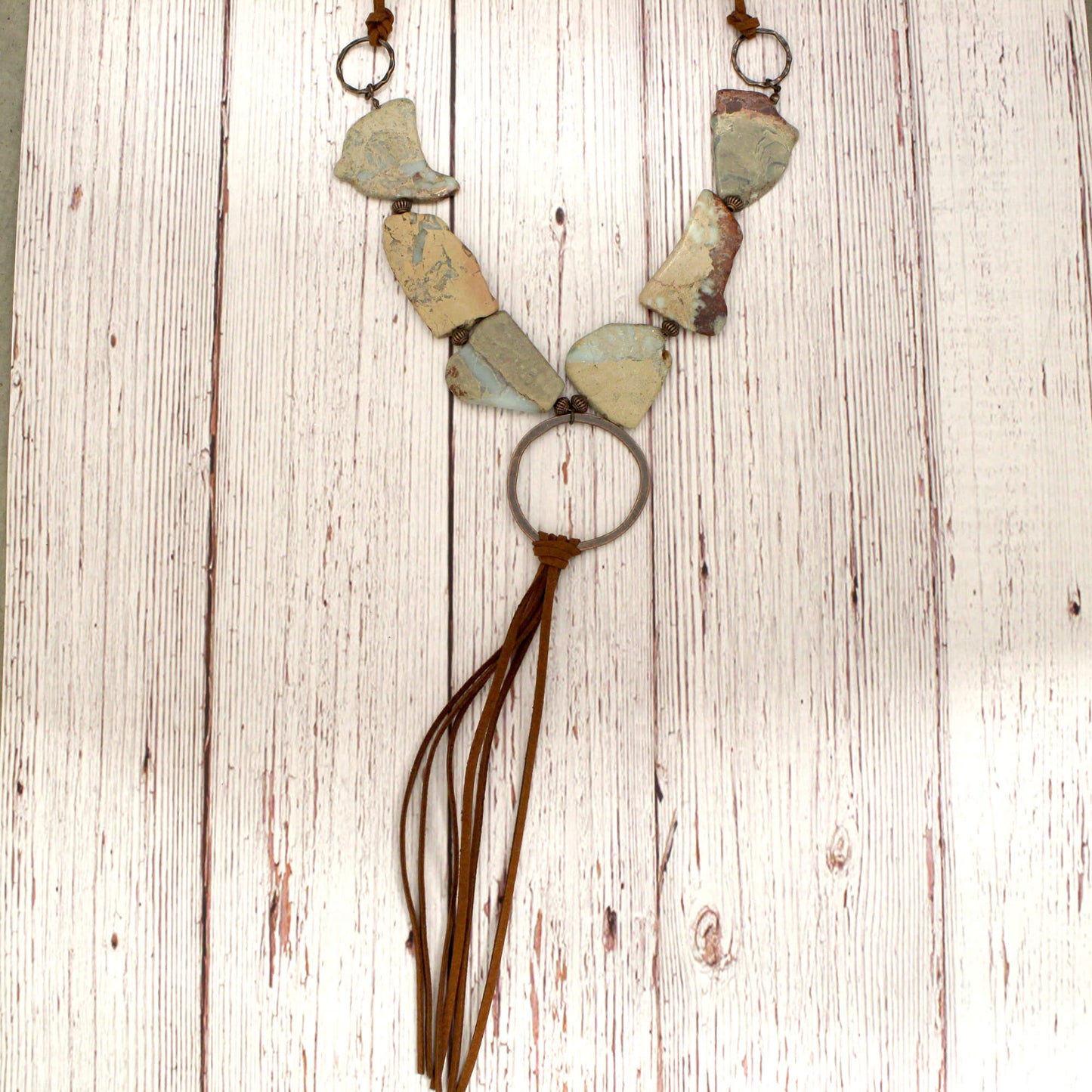 Genuine Slabs of Aqua Terra make up this necklace. Variegated stones blend easily with a variety of colors. 24" in length, adjustable to 30" with self-tie closure makes it great for layering Copper hoop is accented with fringe tassel that is approx. 9" Although your item will resemble the photo, each piece is created by hand, so no two are identical.