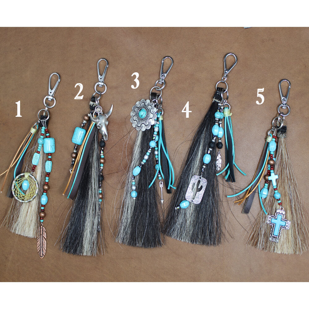 A tassel made from two colors of genuine horsehair is finished with a handwoven horsehair knot.  Each tassel has its own unique adornments and may vary slightly from images. Measuring 9 inches including sturdy swivel hook. Use on purse, bags, home décor, crafts, anything you can clip to! Choose from five designs. Handcrafted in the USA.