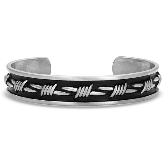 An antiqued silver-toned uni-sex cuff bracelet with a center main barbed wire design. A silver-toned barbed wire design runs down the center of the 1/2"wide cuff with a heavy black background. Smooth lines in a matching silver-tone finish off the edge of the cuff bracelet. One size fits most.