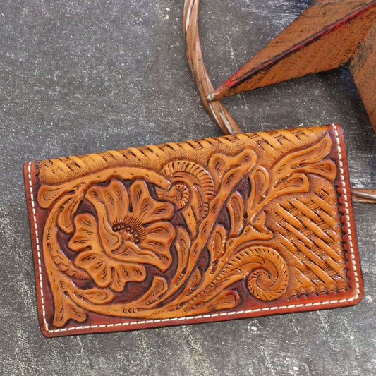 Brown leather wallet with floral tooling on a gray surface