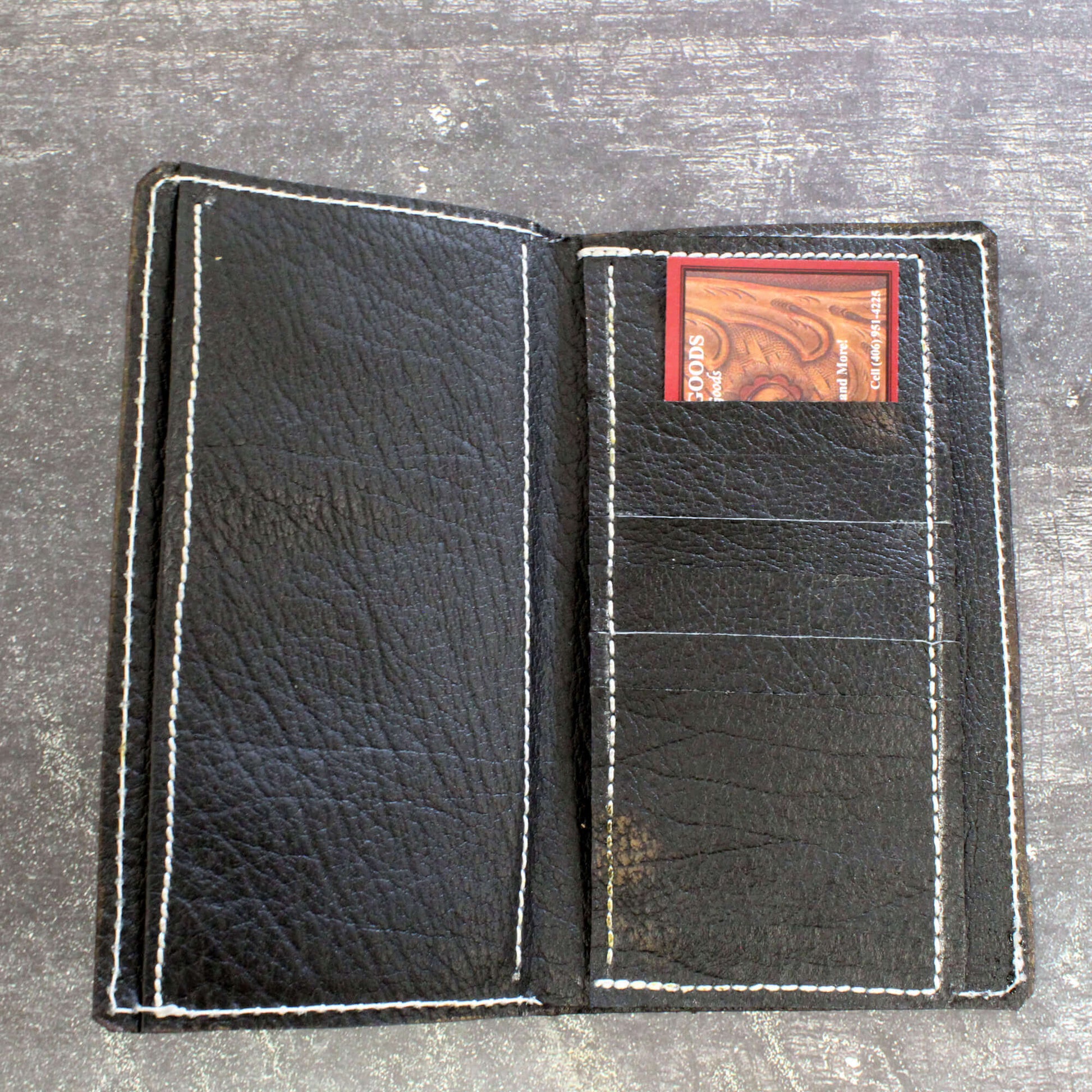 Black leather wallet with a card holder on a gray surface