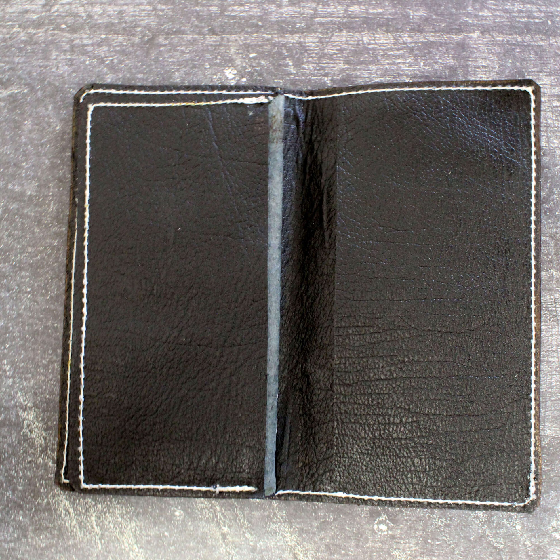 Black leather wallet open on a gray surface