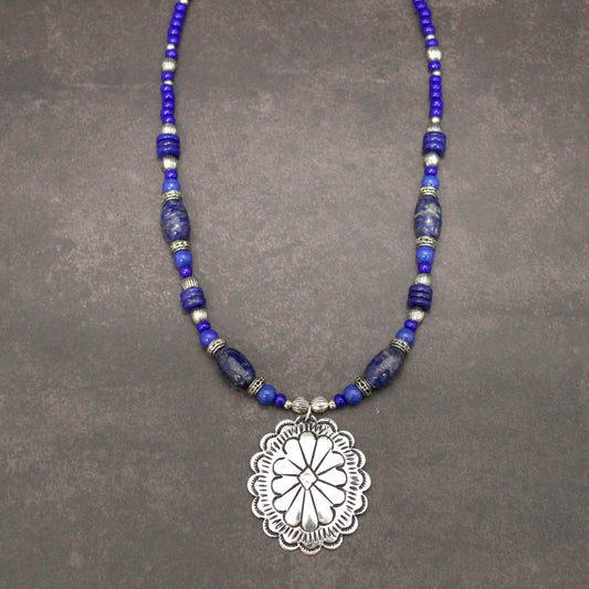 Perfect with Denim! A silver concho with Lapis Lazuli stones. The benefits consist of a powerful intense blue stone used to open minds and give enlightenment. This measures 18″ and an additional 1.75 pendant with an extender.&nbsp; Each piece is unique and may vary slightly.