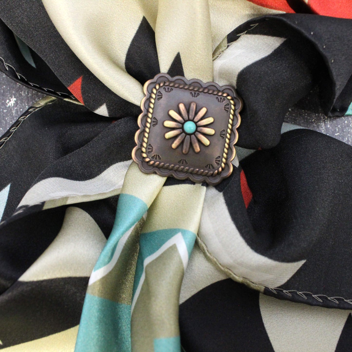 Beautiful square scarf slide with scalloped edges and a turquoise center with windmill like design. Measures 1-1/2" with back loop for a modern decorative ring to secure your western silk scarf. 