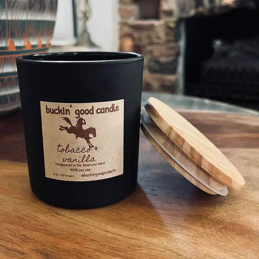 Buckin' Good Candle in a black jar with a wooden lid, featuring tobacco and vanilla scent label.