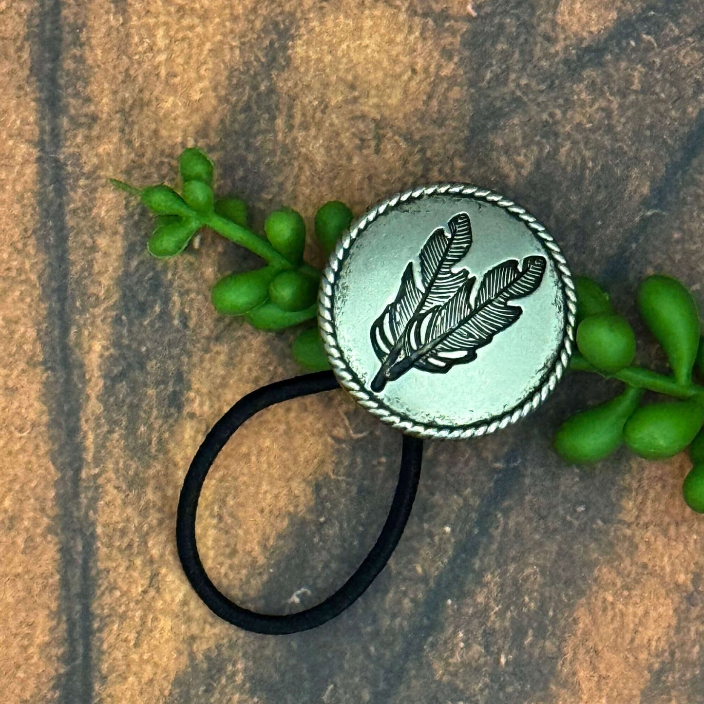 Vintage German silver-plated concho ponytail holder with feather design attached to an elastic hair band.