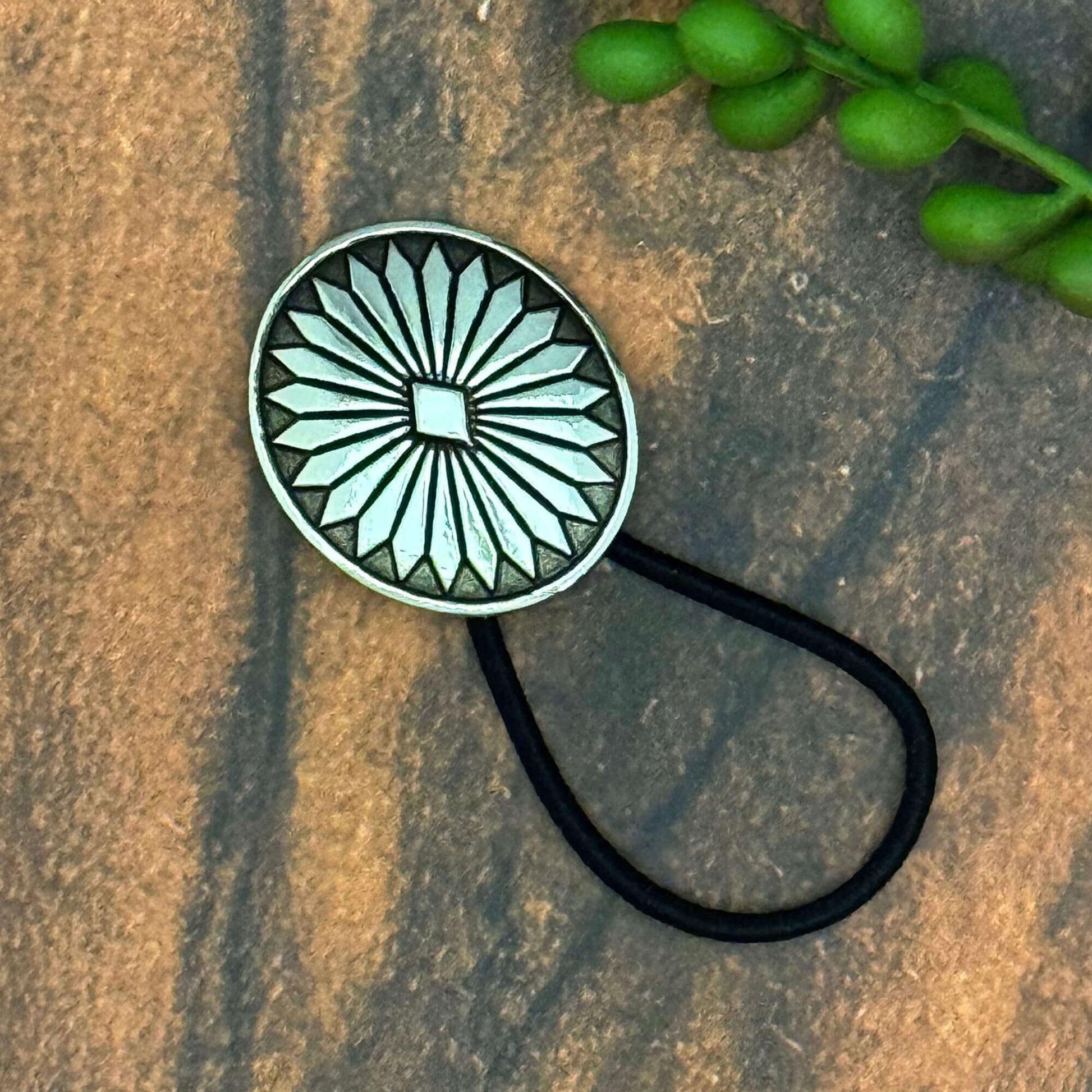 Vintage German silver-plated concho ponytail holder on a black elastic band, decorative hair accessory.