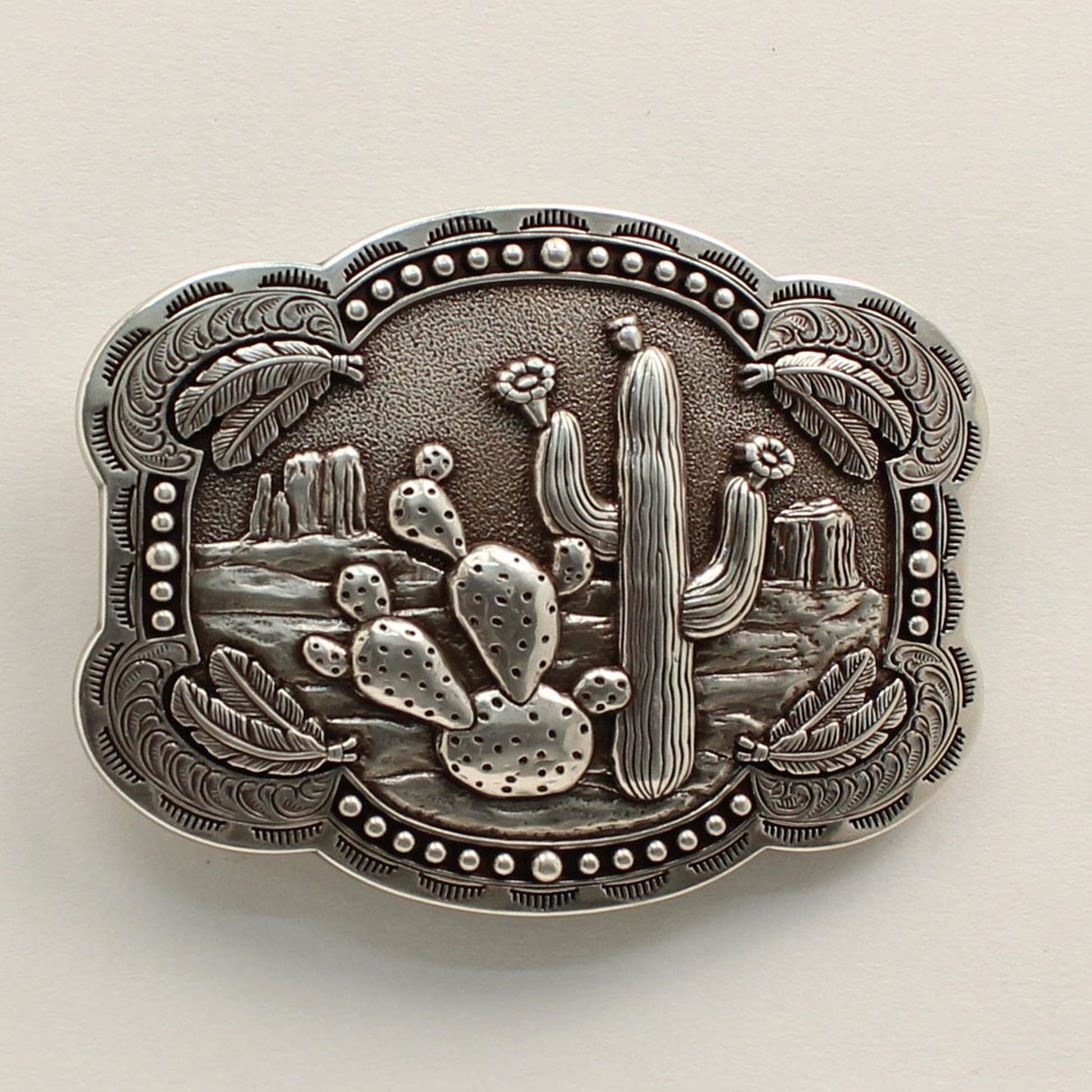 <span data-mce-fragment="1">This rectangle western buckle features a smooth edge with an antique desert scenery in the background with stamped cactus. There is western scrolling and feathers on the corners and small dots on the edges.&nbsp;</span><span data-mce-fragment="1" lang="EN-US">Measures: 3-3/4 x 3-1/4 Imported</span>