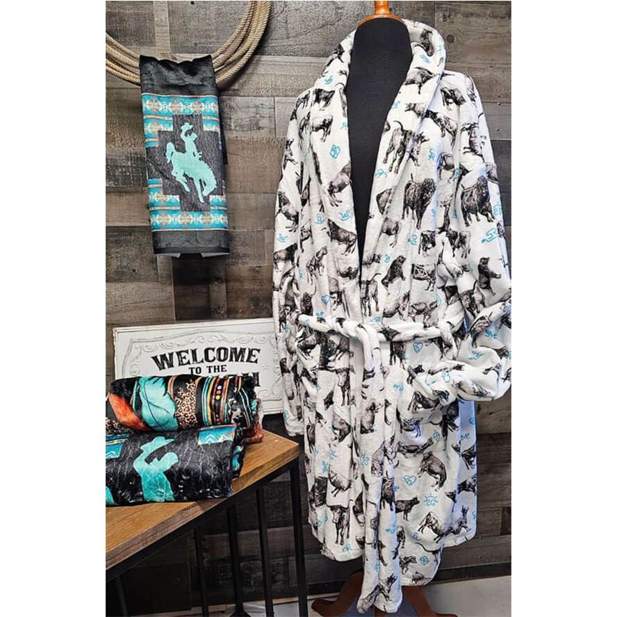 Cozy robe with cow pattern on a mannequin against a wooden wall background.