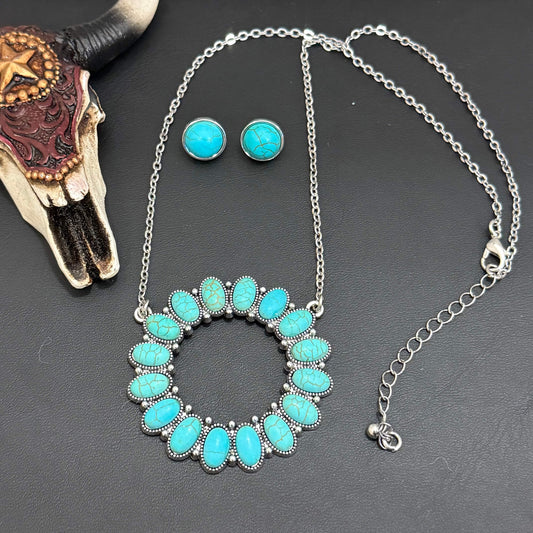 Turquoise necklace and earrings on a dark surface with a cow skull.