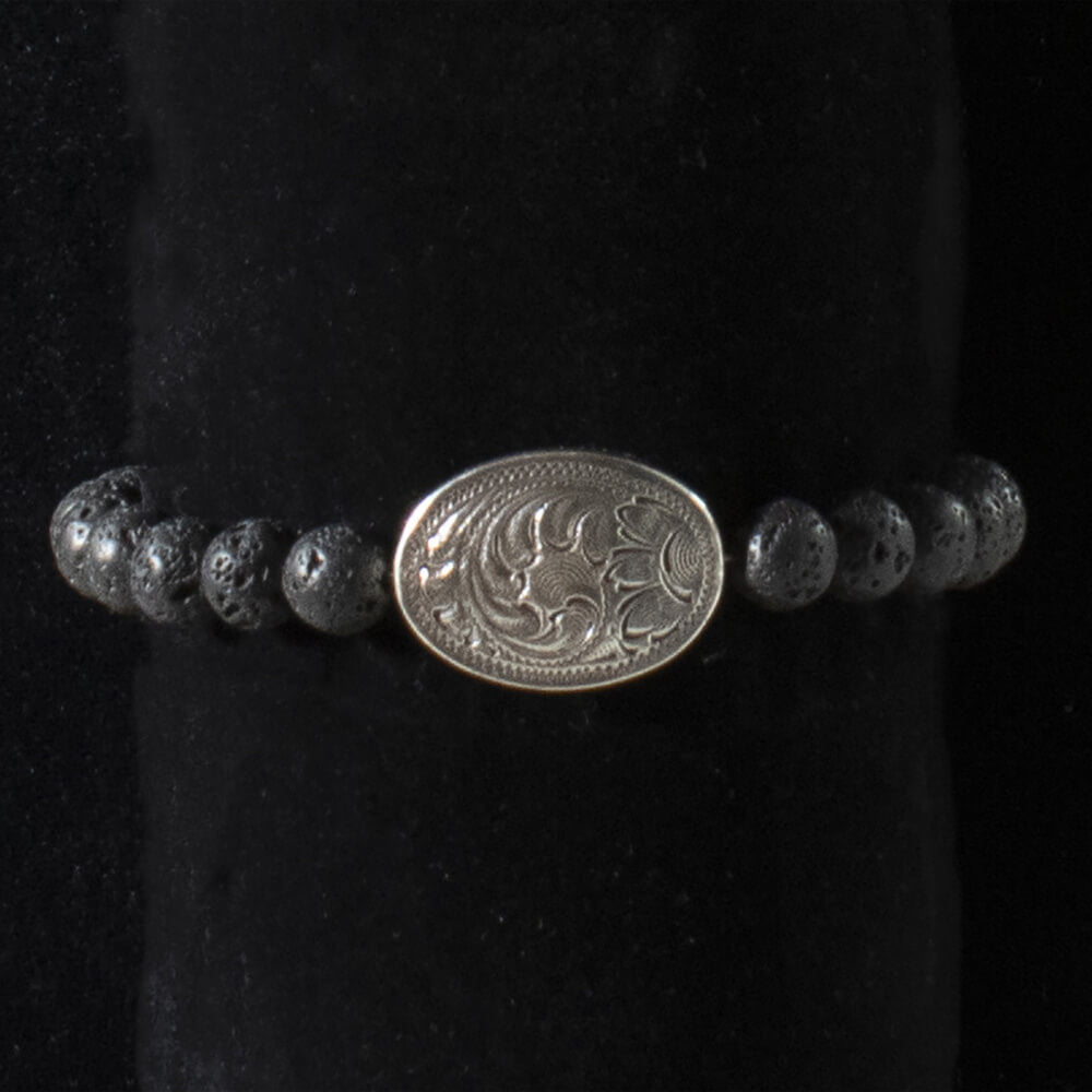 Cool cowboy style concho bracelet with lava stone beads. Hip, simple and manly stretchy pullover bracelet for cowboys or the stylish western man. Antique silver oval concho in the center that is engraved with a floral pattern. 