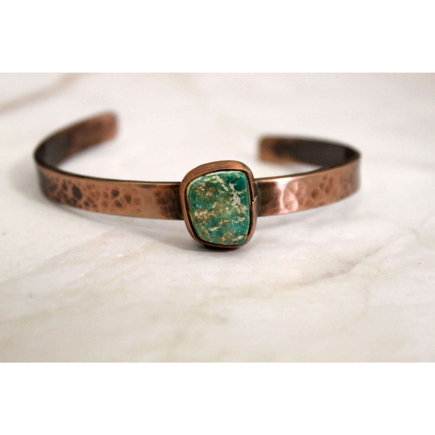 Copper bracelet with a green stone on a white background