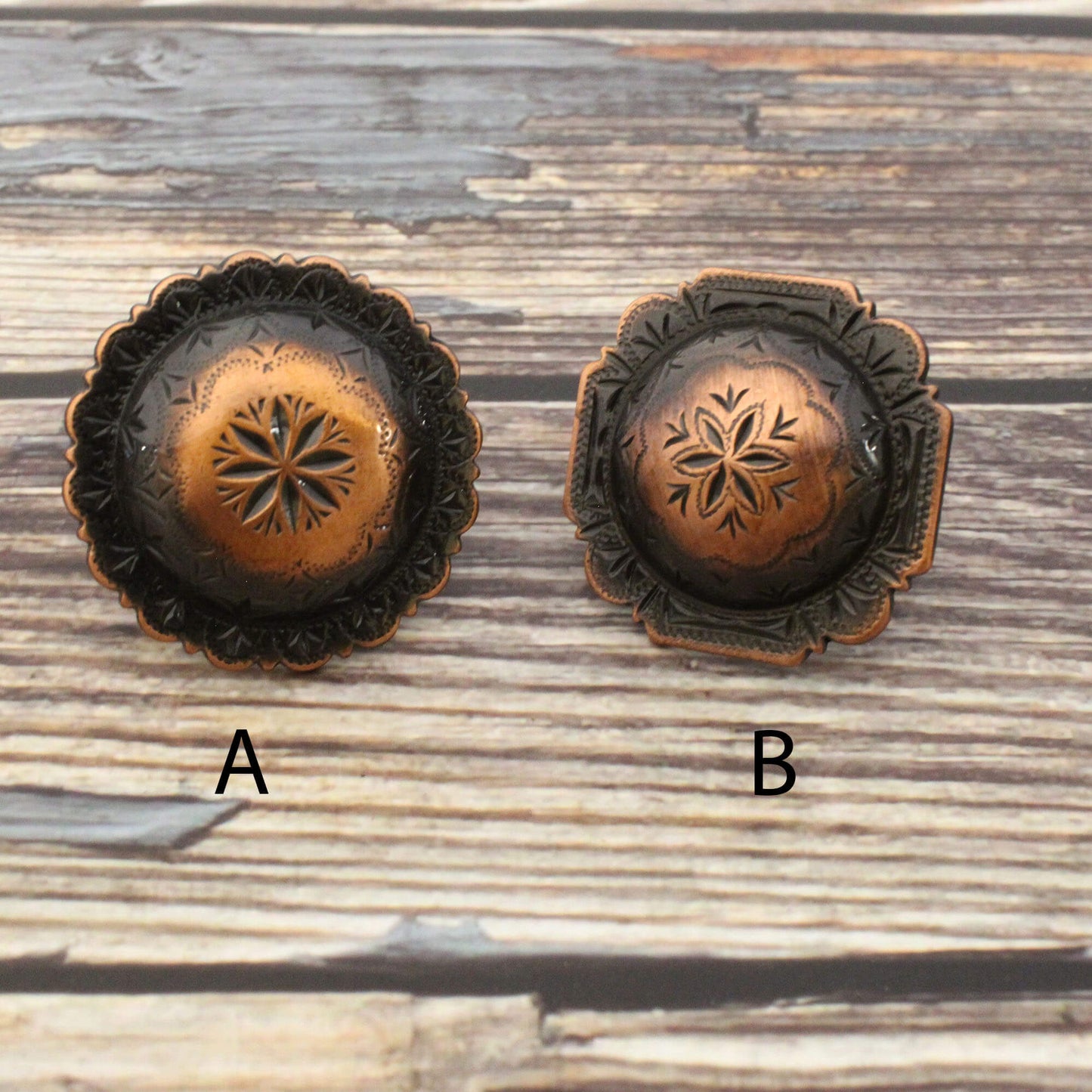 Two bronze-colored decorative buttons on a wooden surface.