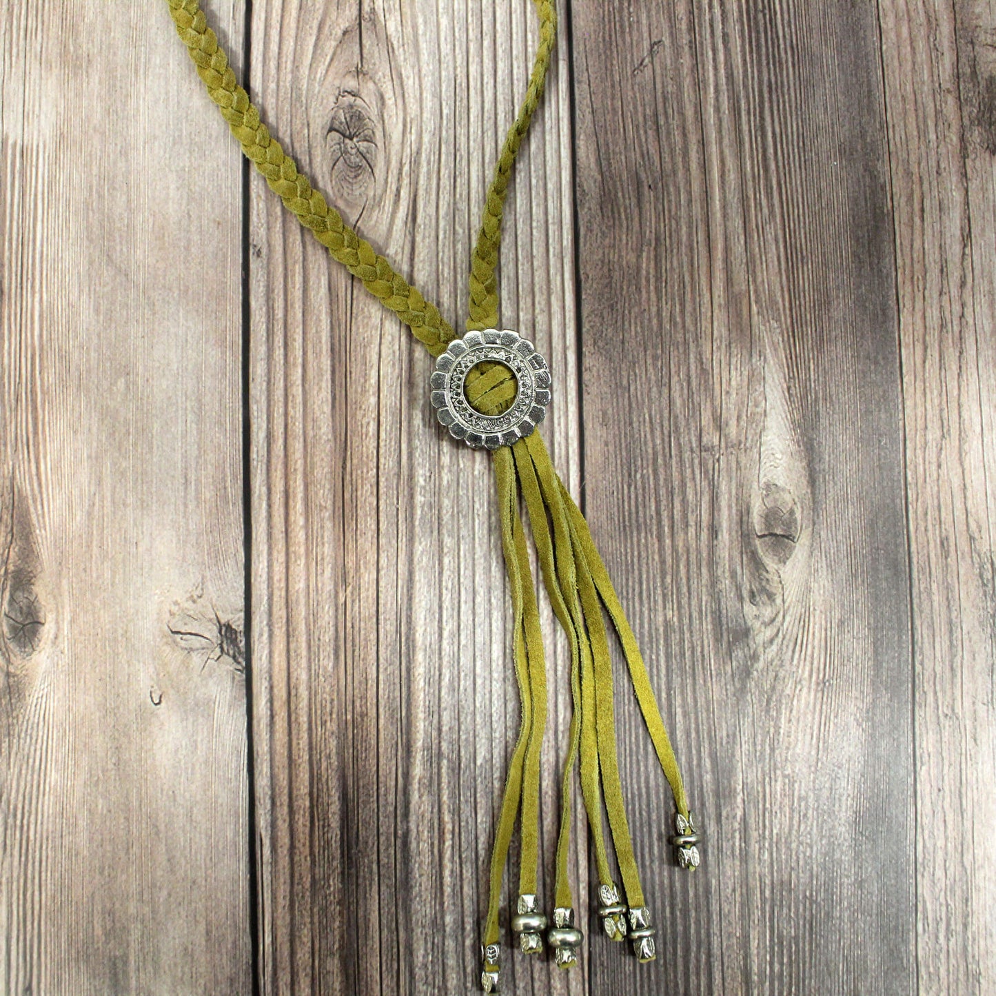 With its standout southwestern inspired details, this necklace makes a stylish statement whether dressed up or down. The pop of mustard suede looks great paired with your favorite tees, tanks, or blouses, while the silver engraved Concho pendant adds a touch of shine. The fringe trim sways with your movements for fluid, boho flair. Measures 38" long.