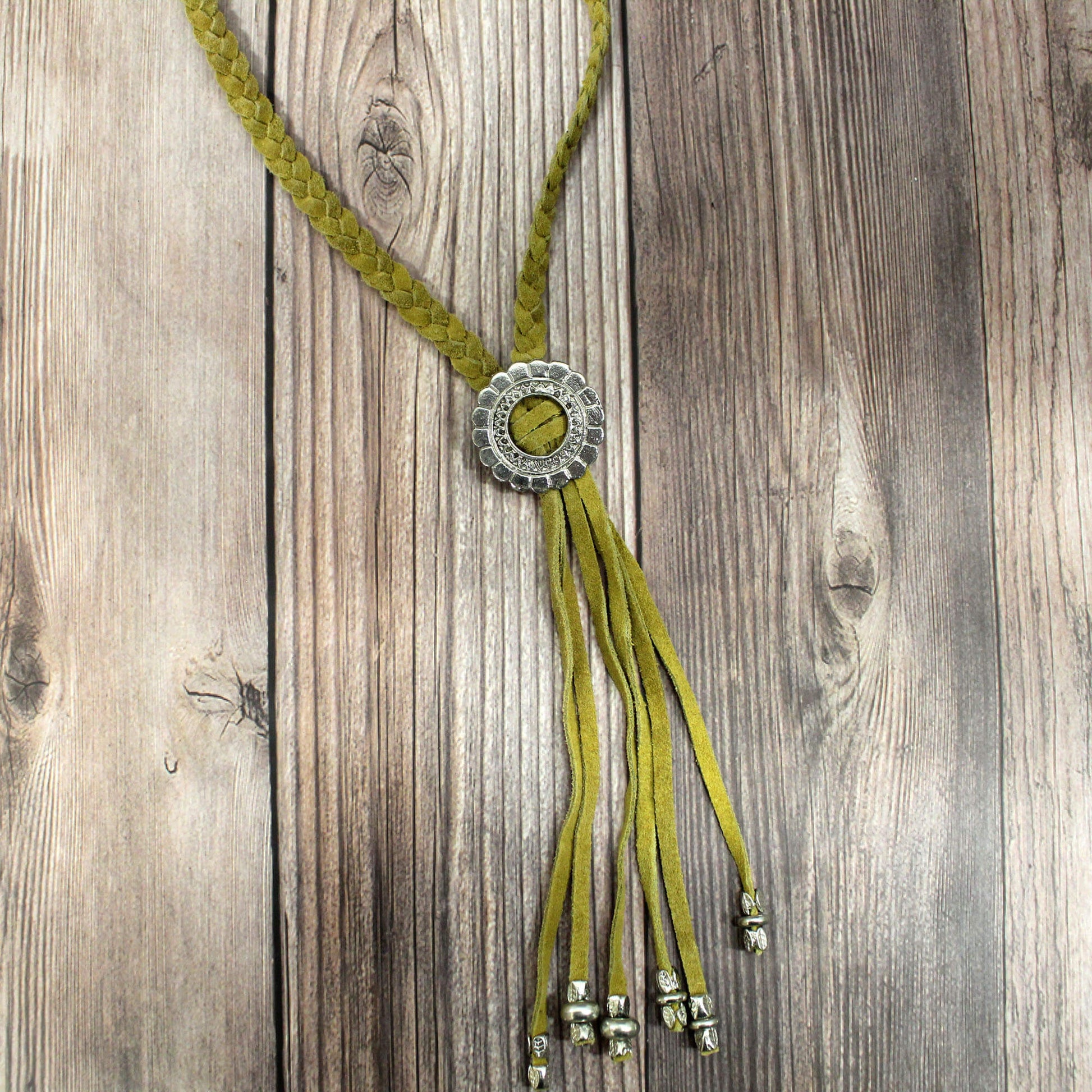 With its standout southwestern inspired details, this necklace makes a stylish statement whether dressed up or down. The pop of mustard suede looks great paired with your favorite tees, tanks, or blouses, while the silver engraved Concho pendant adds a touch of shine. The fringe trim sways with your movements for fluid, boho flair. Measures 38" long.