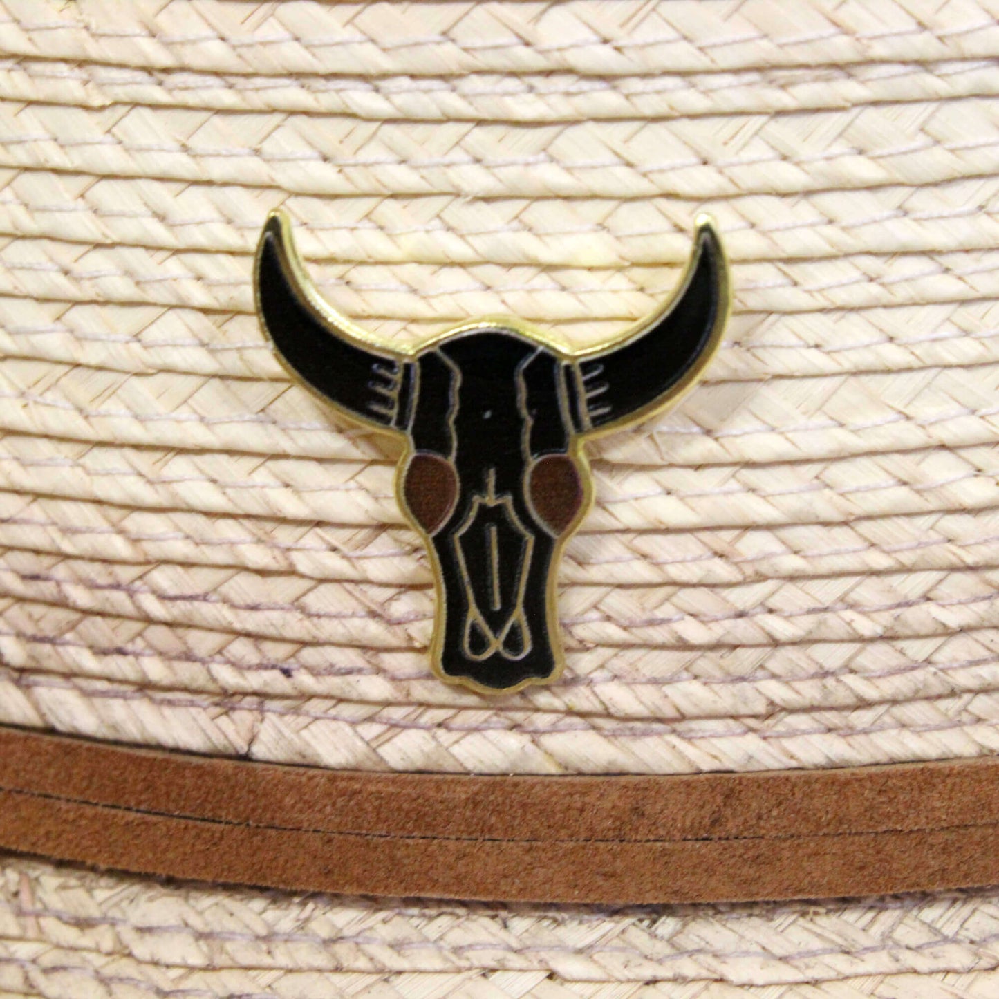 Black bull skull emblem on a straw hat with a brown band