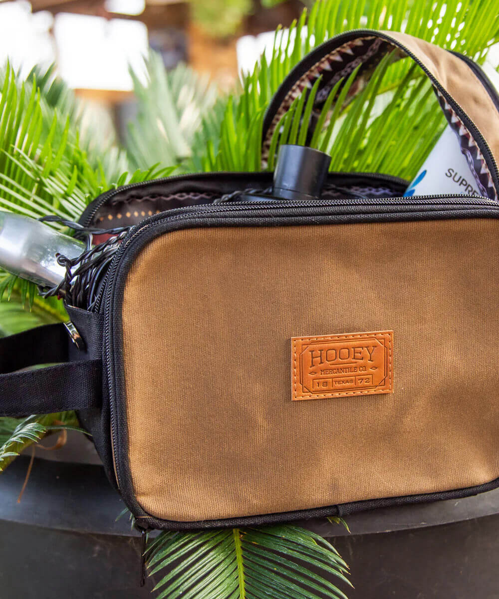 Brown Cowboy Western Toiletry Travel Bag displayed among greenery, showcasing its rugged design and practical features.
