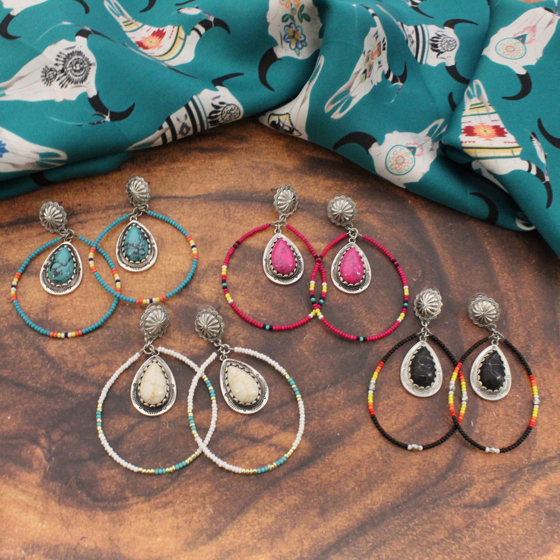 Set of earrings with colorful beaded loops on a wooden surface with fabric in the background