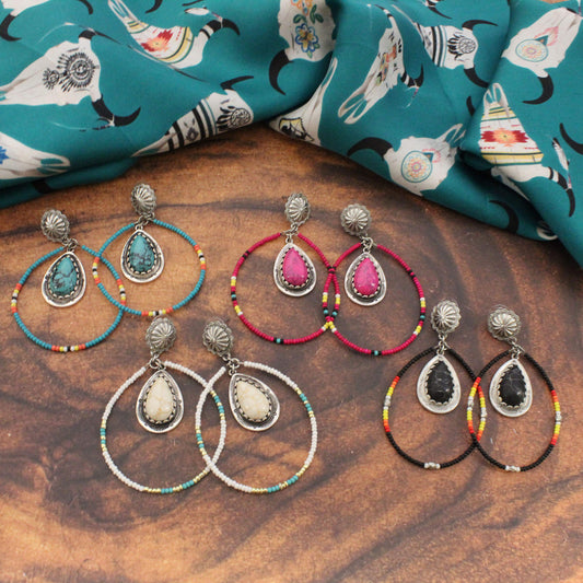 Set of earrings with colorful beaded loops on a wooden surface with fabric in the background