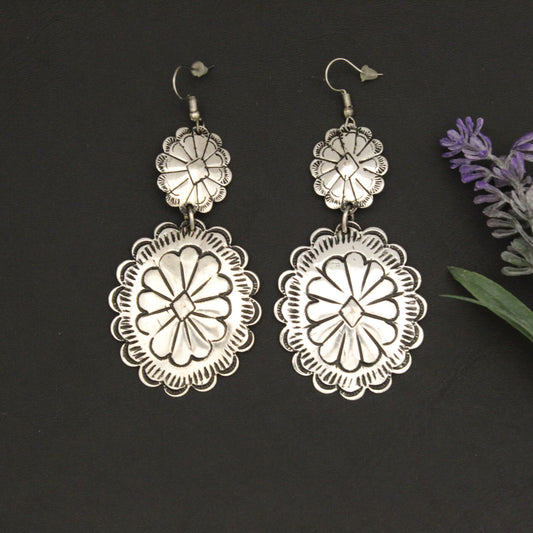 Silver floral earrings on a dark background with lavender flowers.