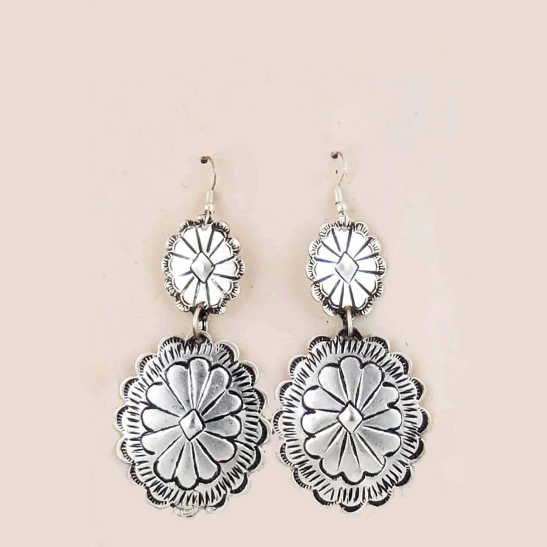 Silver floral earrings on a beige background