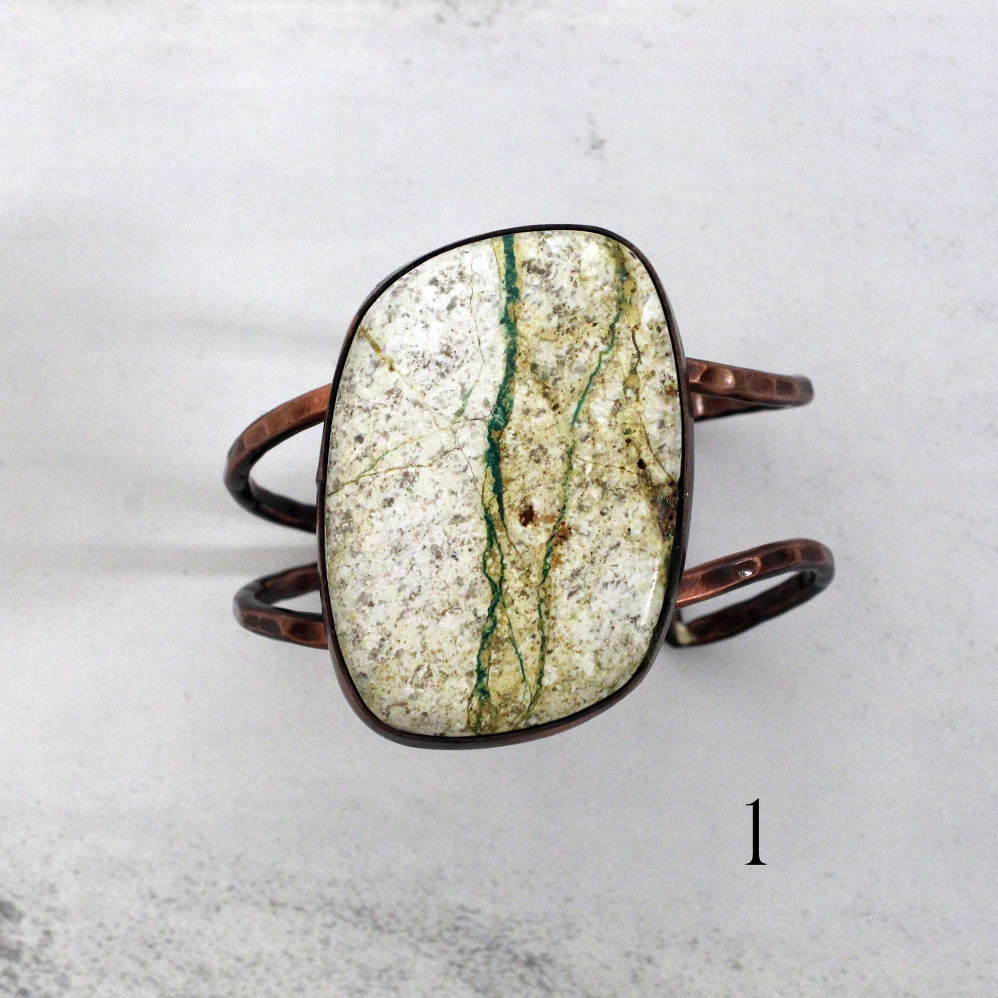 Marble-patterned stone bracelet on a light gray background