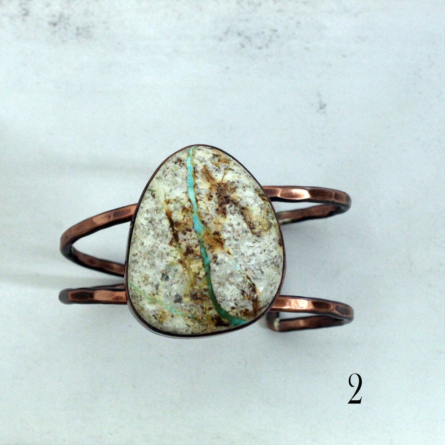 Copper ring with a large, textured stone on a light gray background