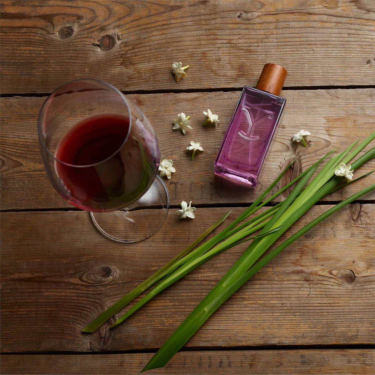 Glass of red tea, purple bottle, and green leaves on a wooden surface