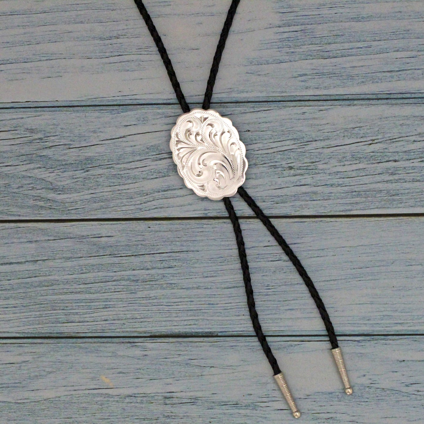 This bolo tie is the perfect blend of tradition and modernity, featuring a beautiful engraved German silver centerpiece and a sleek black leather cord. Whether you're the groom, a groomsman, or a wedding guest, this accessory will elevate your western-inspired look and make you feel confident and stylish.