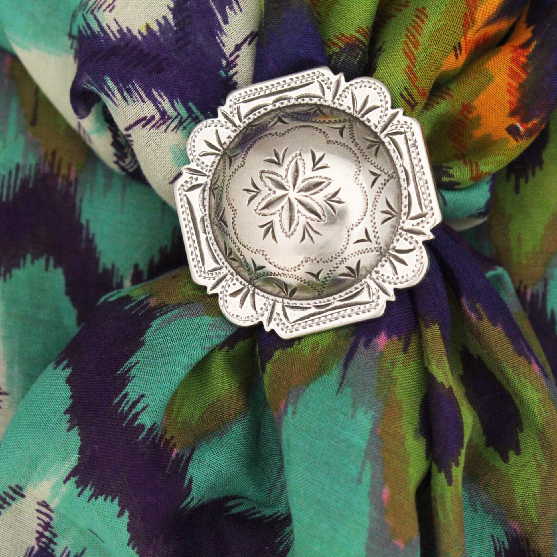 This stunning scarf slide is the perfect way to take your Western-inspired style to the next level. The vintage silver concho closure not only secures your scarf in place, but also serves as a stylish accent piece that commands attention. Measuring 1.5 inches wide, this slide makes a bold statement that complements your favorite cowboy silk scarves. Simply slide it onto your scarf and let the vintage-inspired design elevate your entire look.