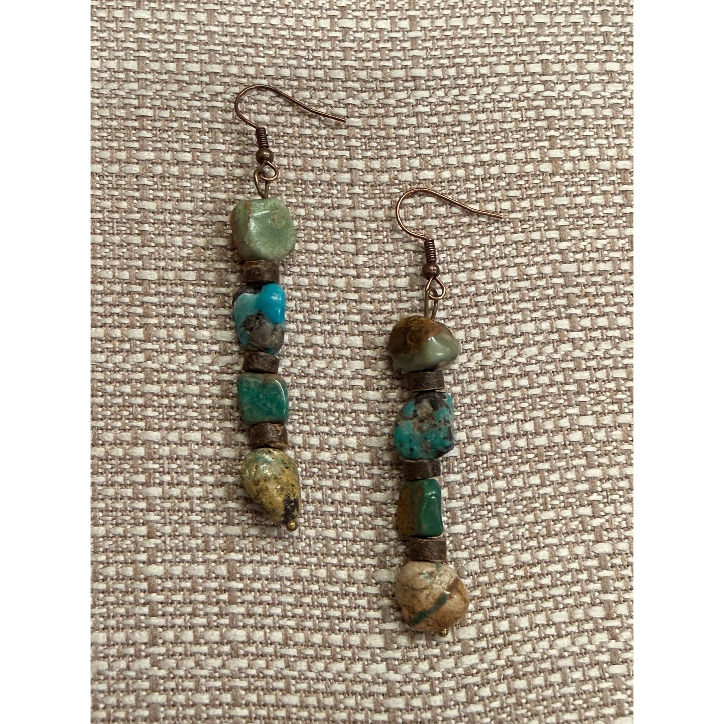 Pair of beaded earrings on a textured fabric background