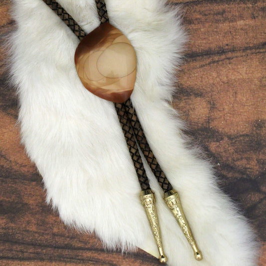 Bolo tie with wooden center and gold tips on a white fur background