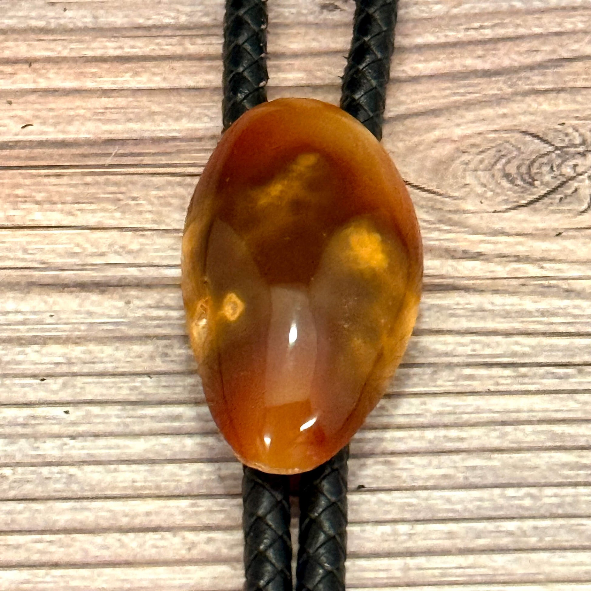 Brown agate stone on a black cord against a wooden background