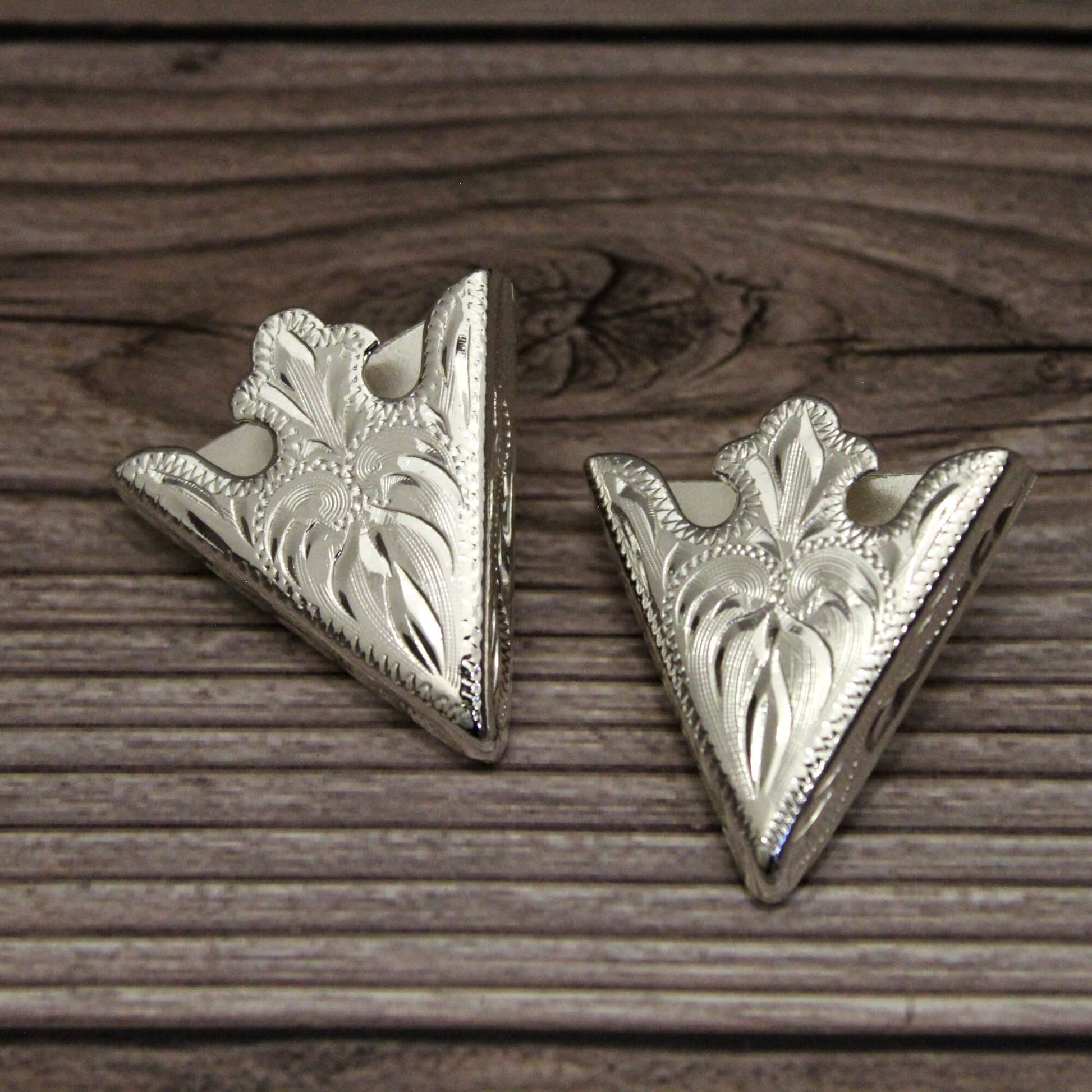 Two silver triangle-shaped decorative items on a wooden surface