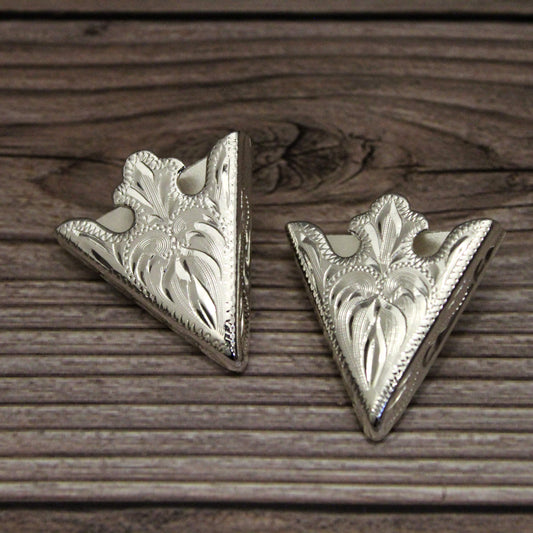 Two silver triangle-shaped decorative items on a wooden surface